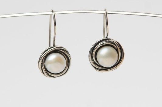 עגילי פנינה תלויים במסגרת מלופפת